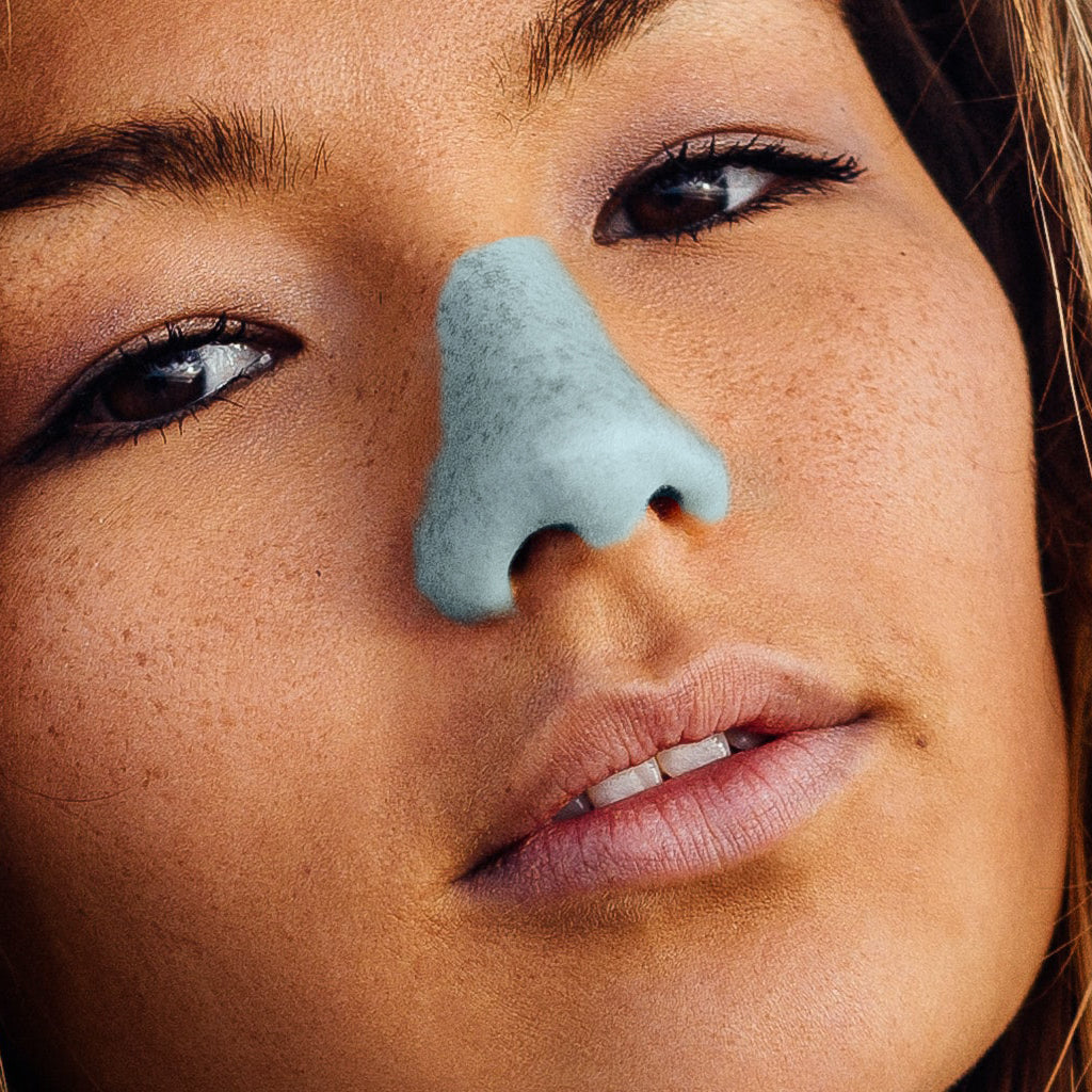 brunette women with freckles and brown eyes wearing Nöz's reef safe sunscreen in the color teal